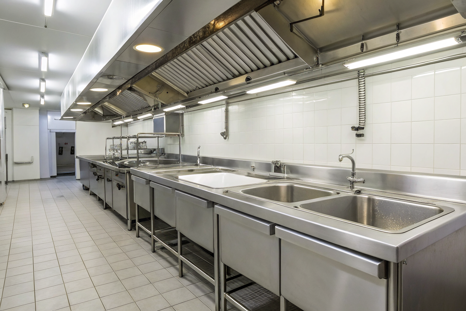 Commercial kitchen with grease interceptors under sinks.
