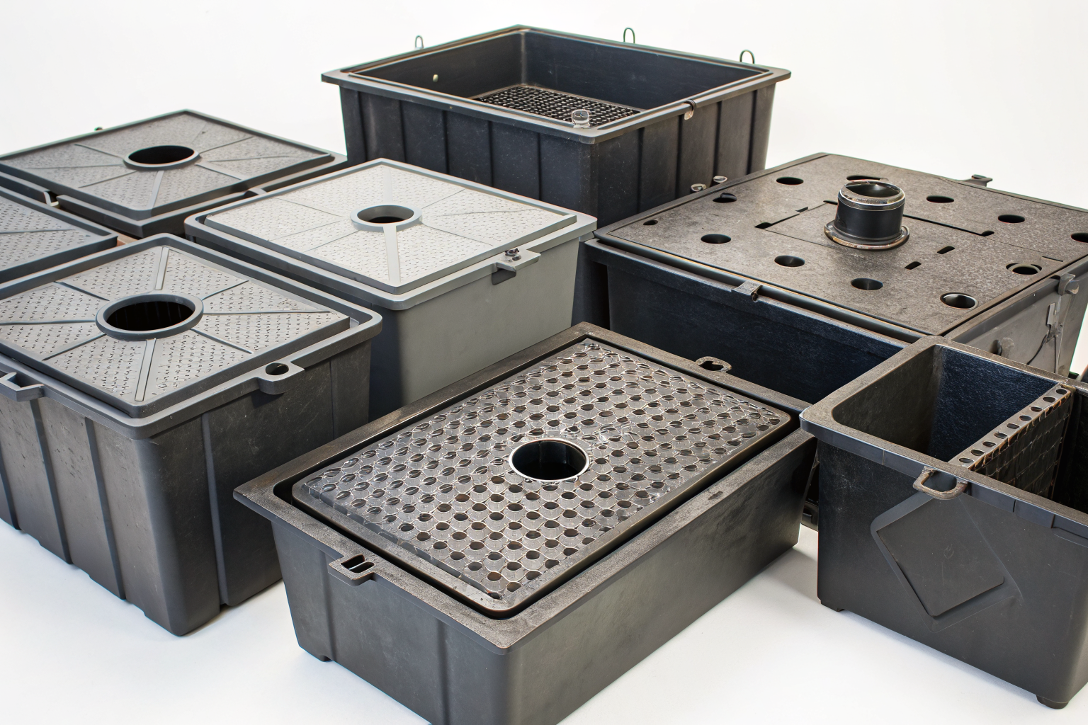 Grease traps labeled by restaurant type in a bright studio setting.